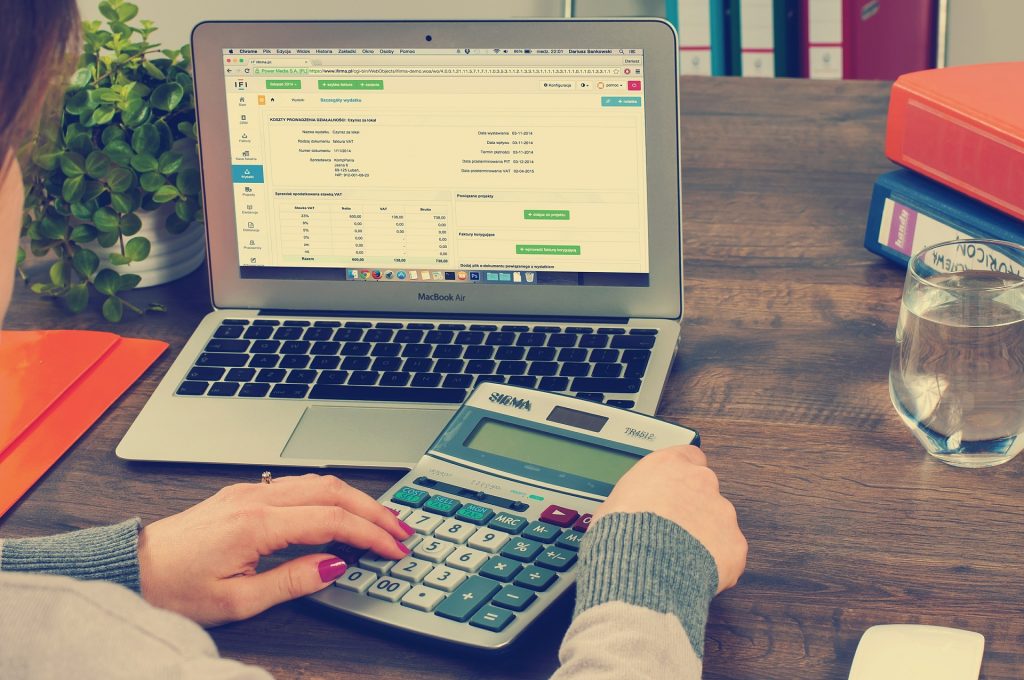 Une femme faisant sa comptabilité à l'aide d'un calculette et d'un ordinateur