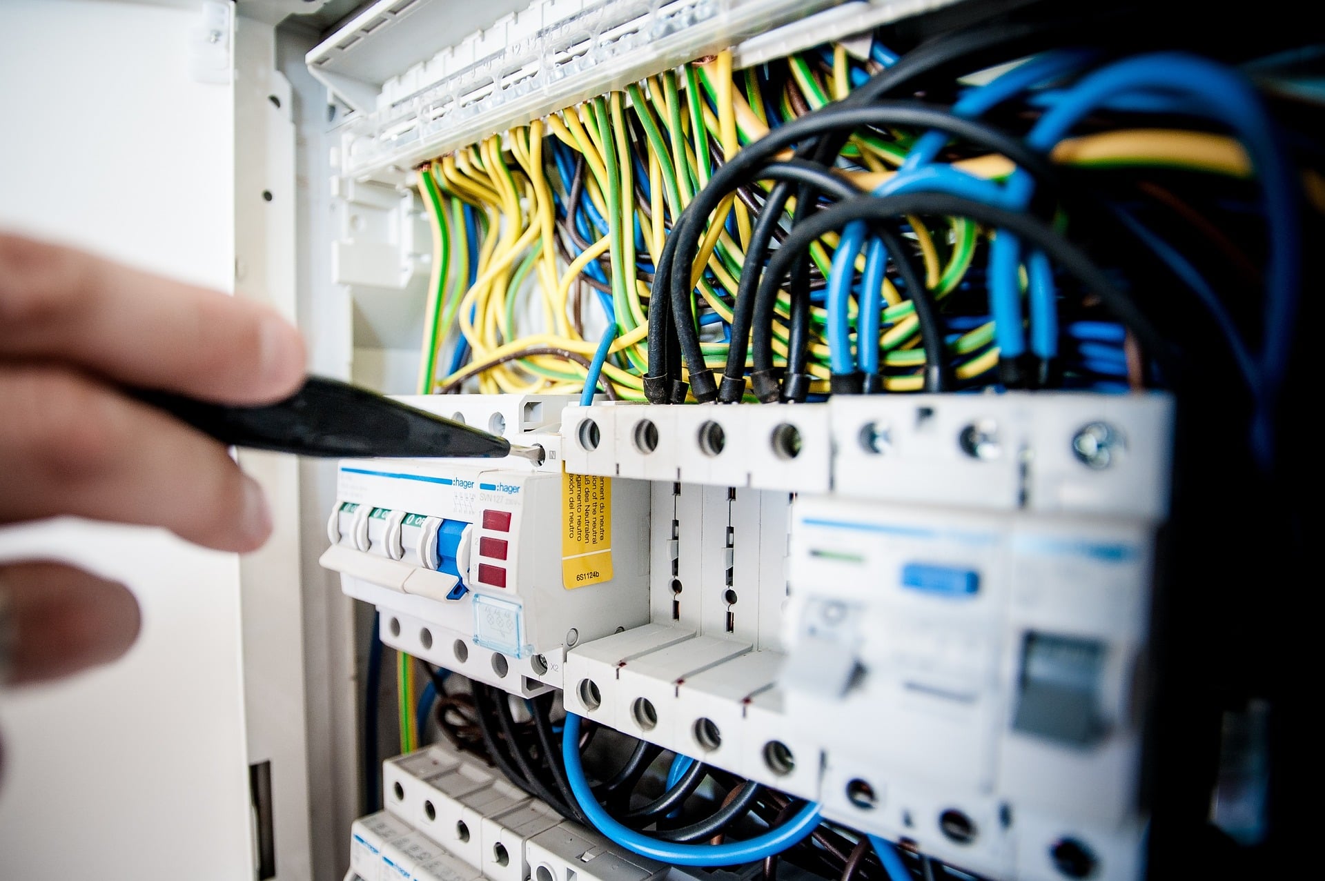 Un electricien qui travail sur un tableau electrique garni de fils